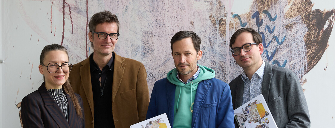 Vier Menschen posieren vor einer bemalten Leinwand im Atelier10.